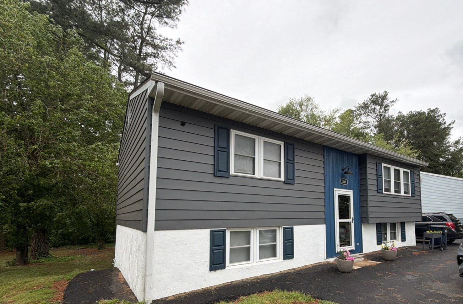 Home surrounded by trees with fresh siding and shutters exterior paint job.