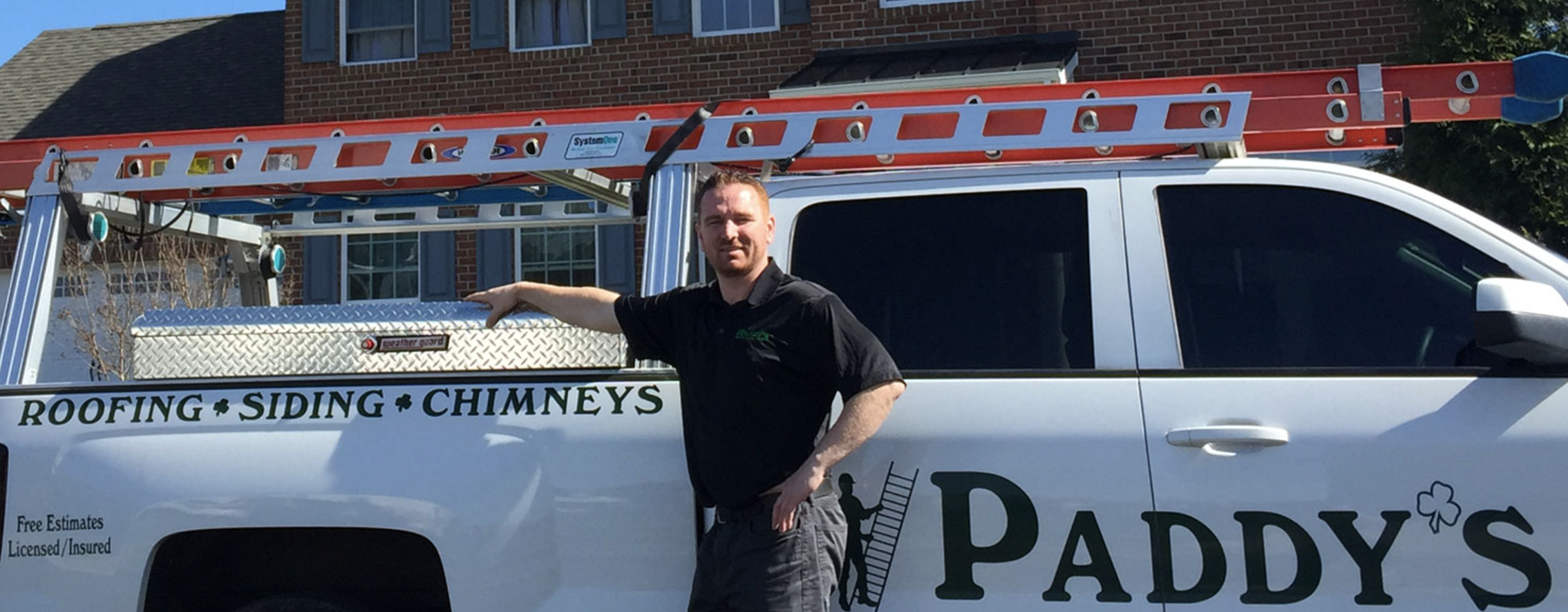 Man Standing in front of Paddy's Roofing work truck with arm on toolbox