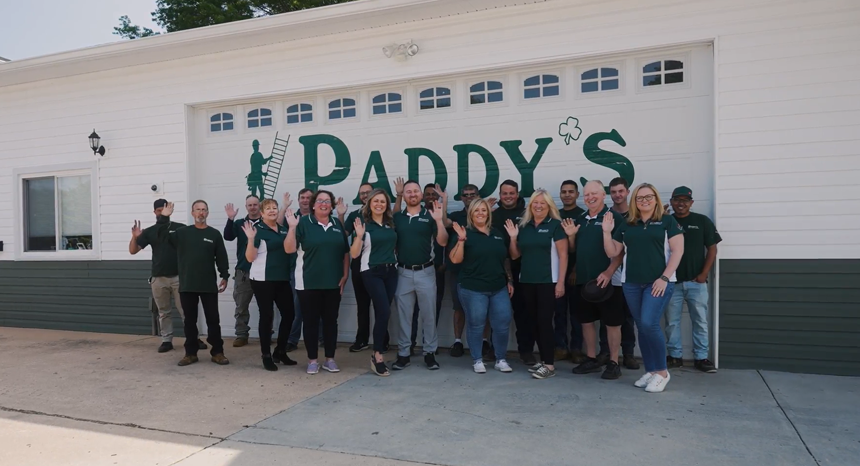 Paddy's Roofing team photo in front of white garage door with 'Paddy's painted in green
