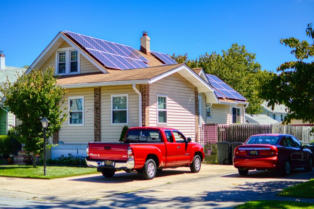 climate impact on delaware roofs: a red truck parks in front of a house with solar shingles.